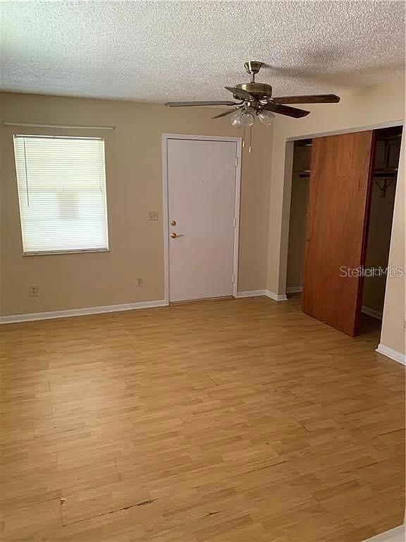 A room with light wood-look flooring, a ceiling fan, a window, and a closet door — 5217 17TH STREET, ZEPHYRHILLS, FL