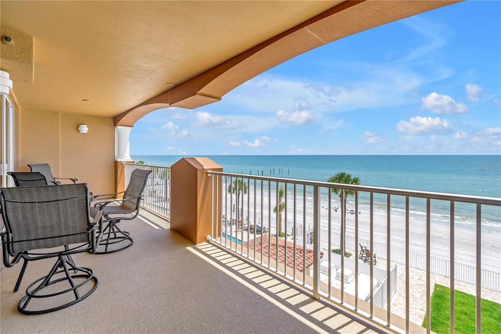 A covered balcony with outdoor chairs overlooks a sandy beach and the ocean — 16326 GULF BOULEVARD UNIT 308, REDINGTON BEACH, FL
