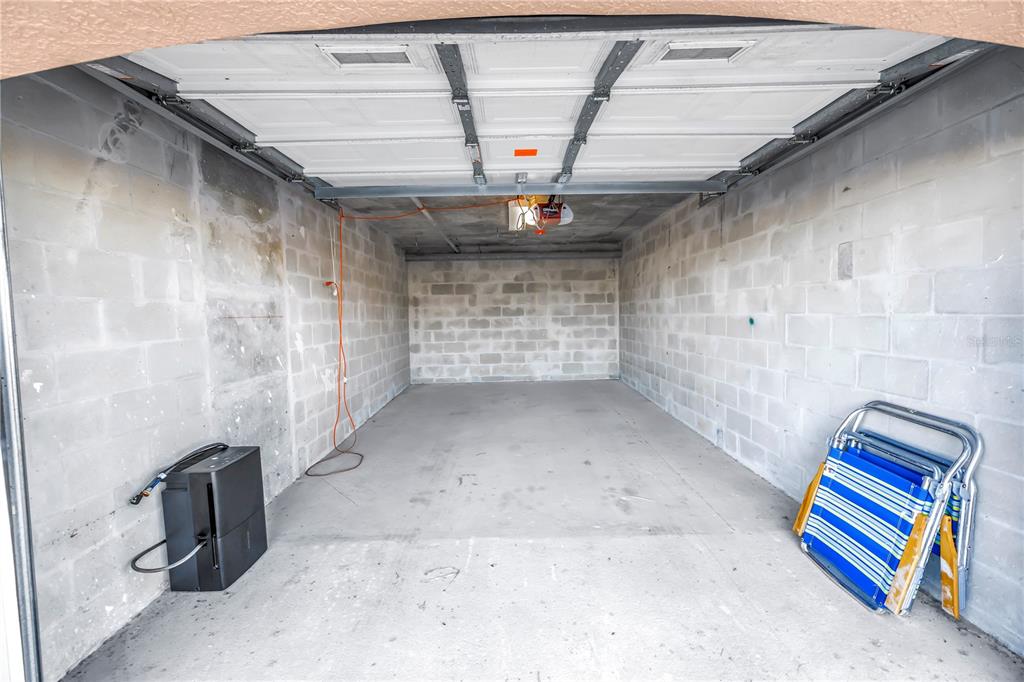 An empty garage with concrete block walls, a concrete floor, and a white sectional door — 16326 GULF BOULEVARD UNIT 308, REDINGTON BEACH, FL