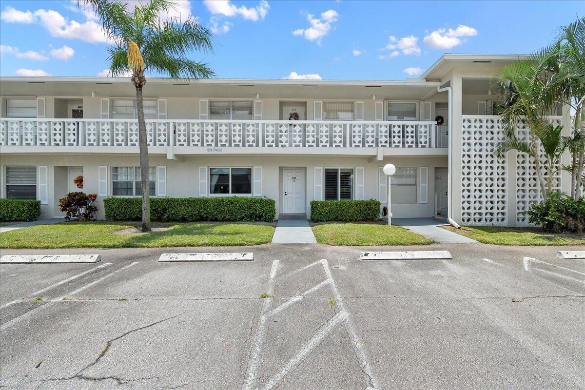 A two-story apartment building with a white facade, balcony, and parking lot in front — 1395 SW 27th Avenue # 102, Delray Beach FL 33445, DELRAY BEACH, FL