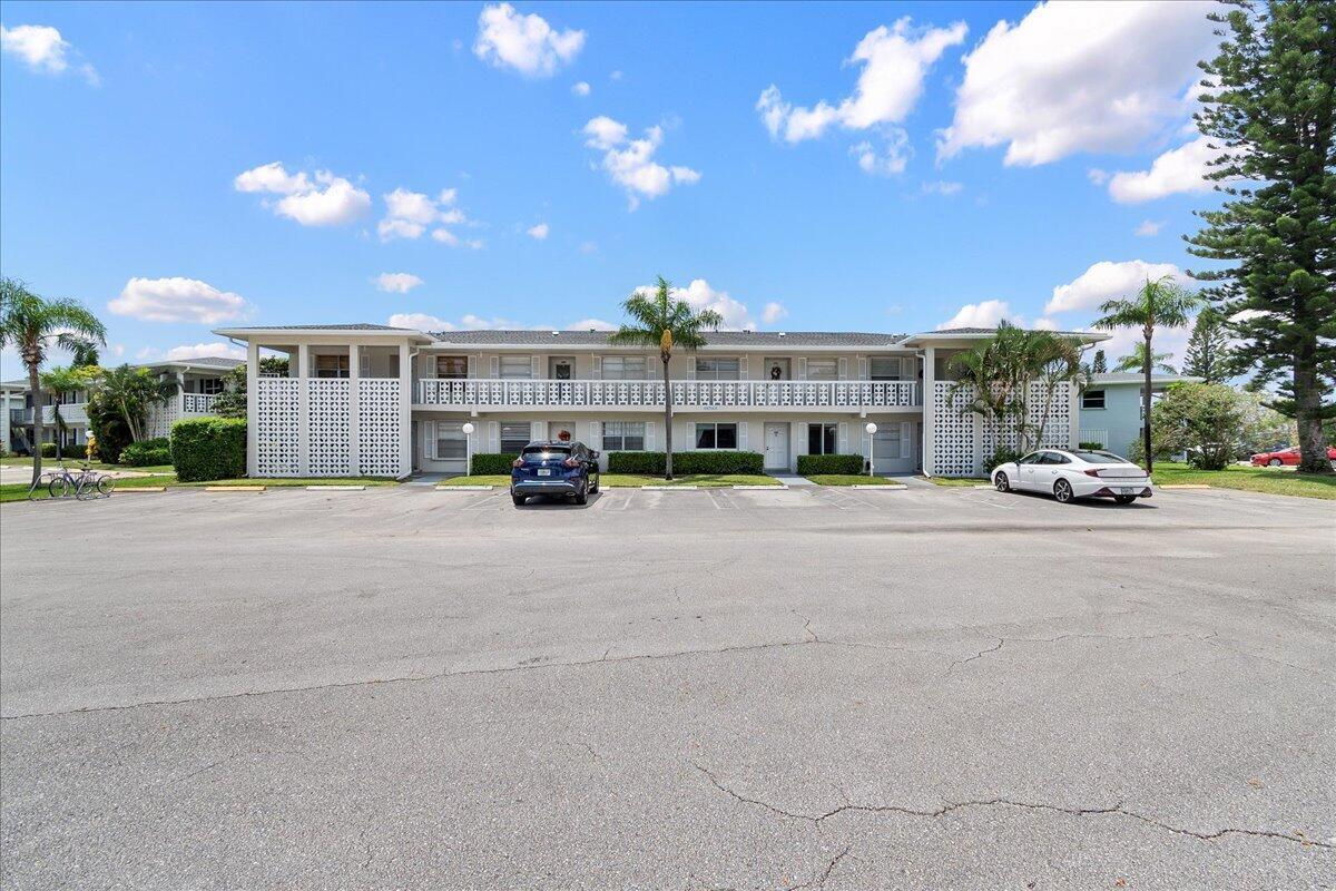 A two-story apartment building with a parking lot in the foreground under a blue sky — 1395 SW 27th Avenue # 102, Delray Beach FL 33445, DELRAY BEACH, FL