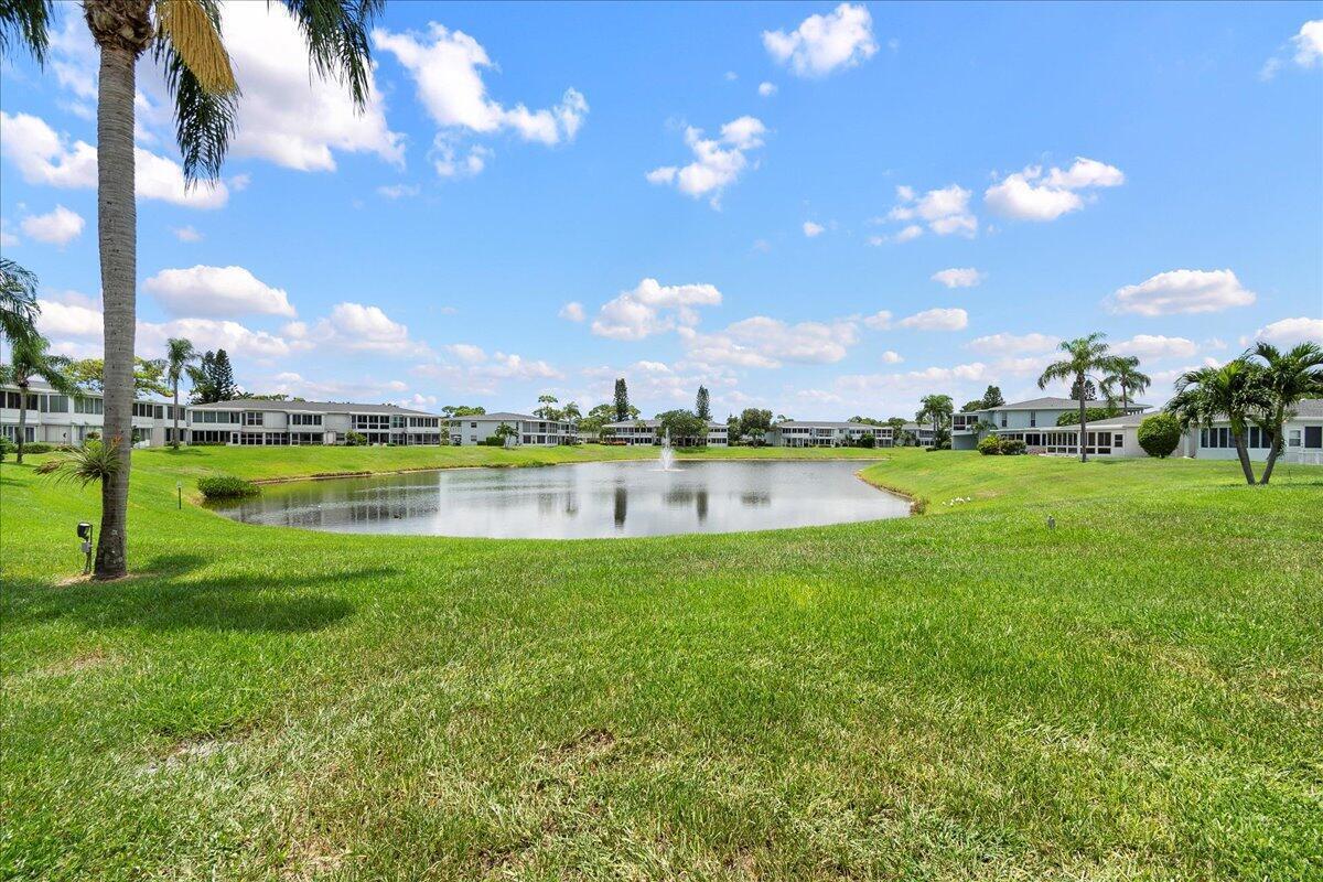 A grassy lawn leads to a pond with a fountain and surrounding residential buildings — 1395 SW 27th Avenue # 102, Delray Beach FL 33445, DELRAY BEACH, FL