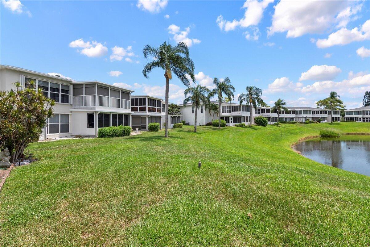 A view of multi-story residential buildings with screened lanais overlooking a grassy lawn and pond — 1395 SW 27th Avenue # 102, Delray Beach FL 33445, DELRAY BEACH, FL