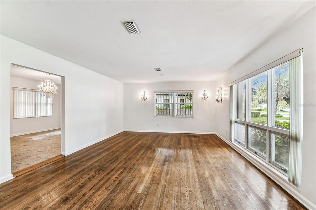 A bright living room features hardwood floors, white walls, wall sconces, and large windows — 4508 HENDERSON BOULEVARD, TAMPA, FL