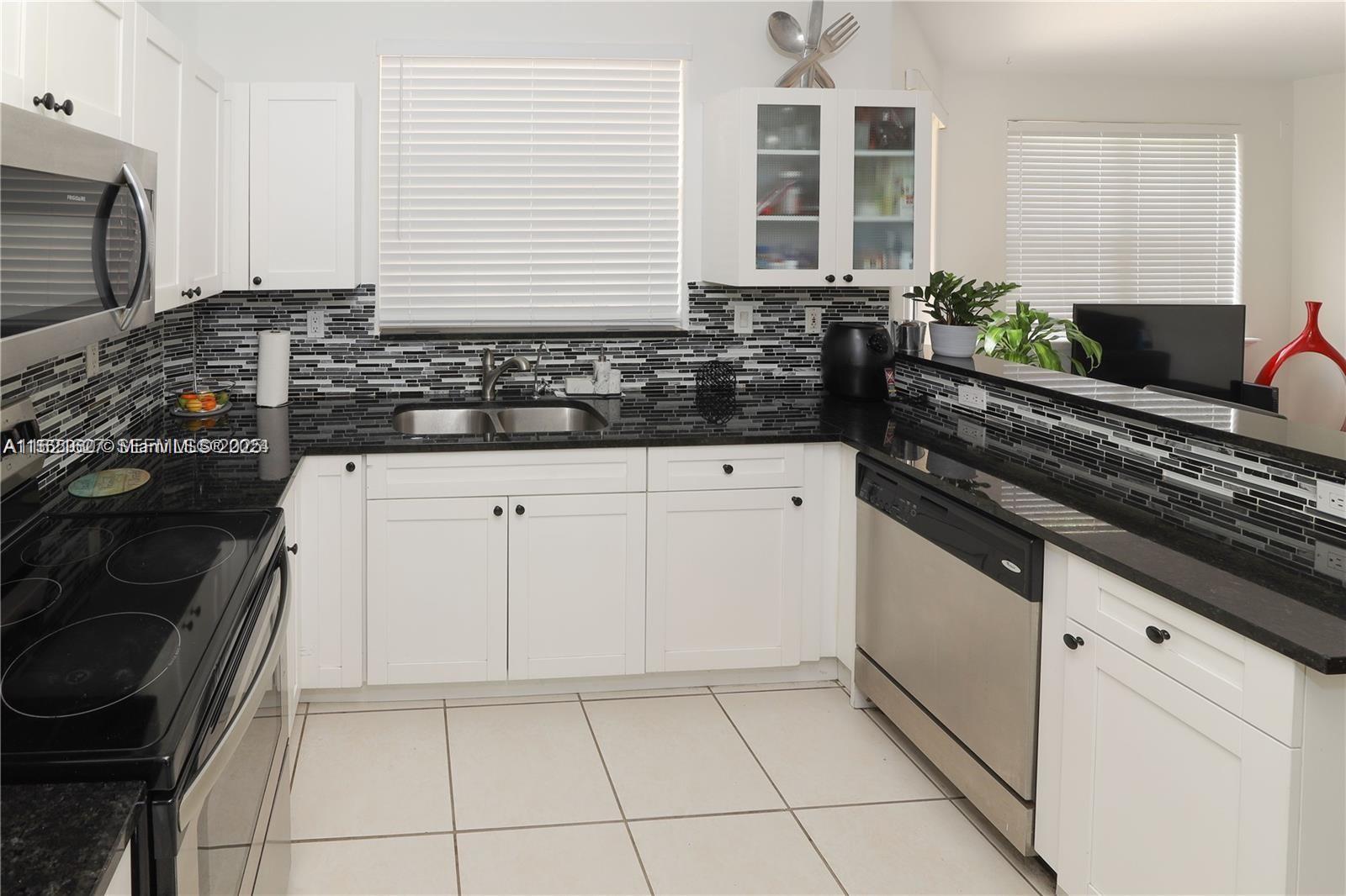 A kitchen features white cabinets, black granite countertops, a tiled backsplash, and stainless steel appliances — 4866 NW 108th Psge # 4866, Doral FL 33178, DORAL, FL