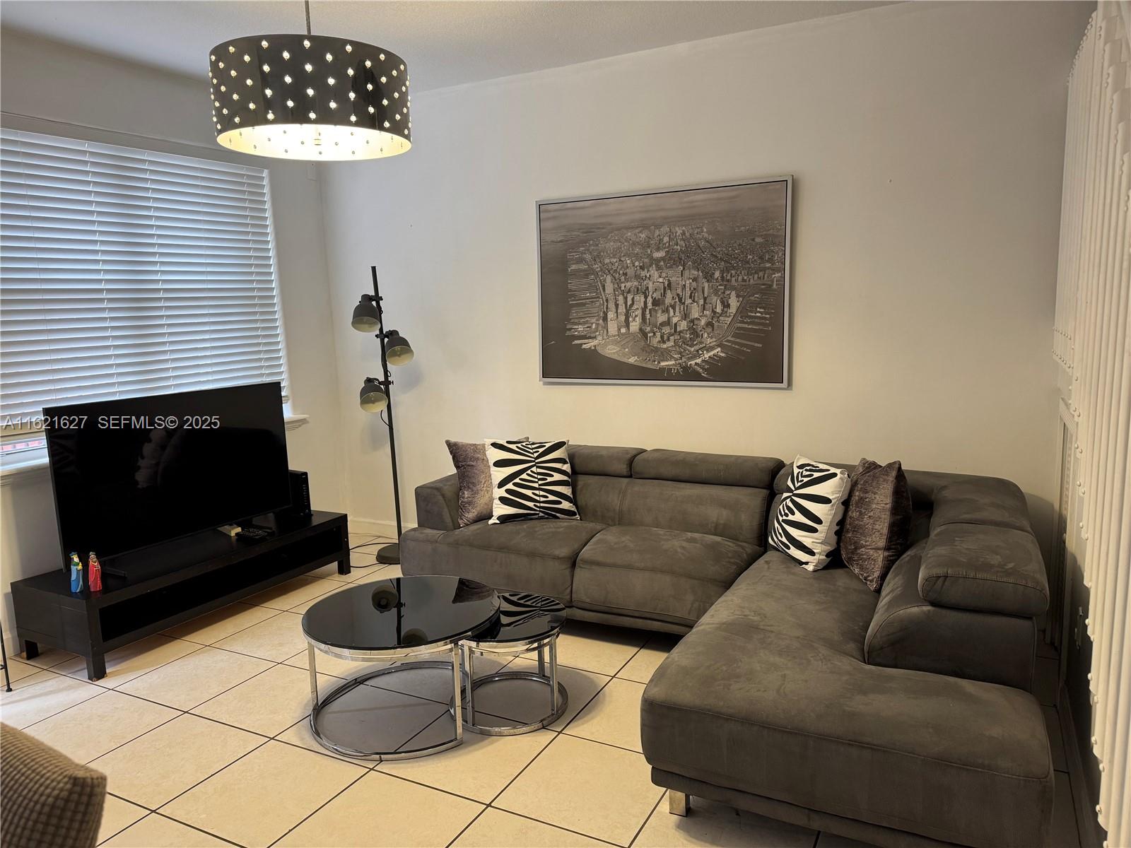 A living room features a grey sofa, a patterned rug, and large abstract wall art — 4866 NW 108th Psge # 4866, Doral FL 33178, DORAL, FL