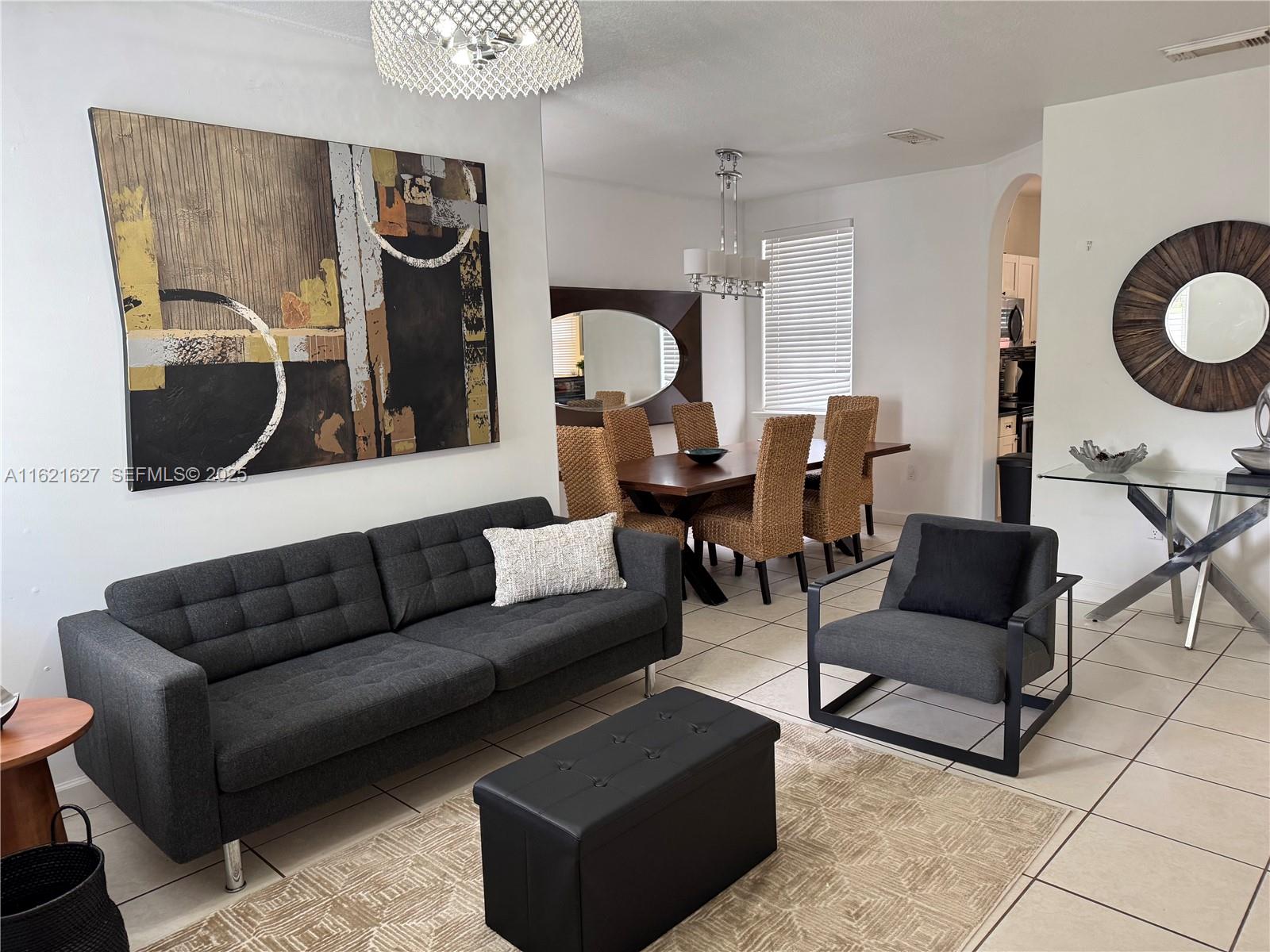 A living room features a grey sofa, a large square ottoman, and a television on a stand — 4866 NW 108th Psge # 4866, Doral FL 33178, DORAL, FL