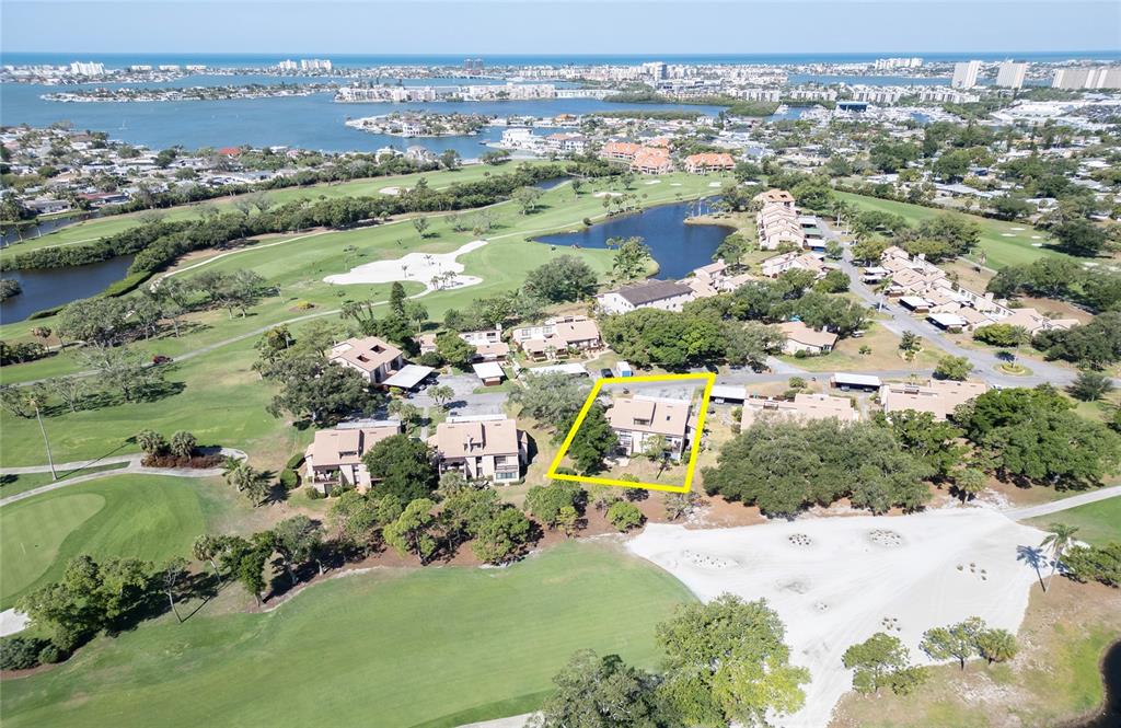 An aerial view shows a residential building highlighted in yellow, situated on a golf course — 6305 PELICAN CREEK CROSSING UNIT D, ST PETERSBURG, FL