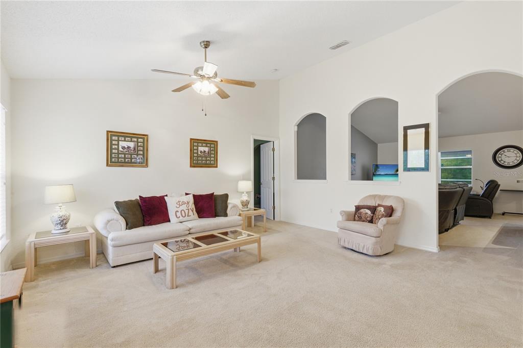 A living room features a white sofa, a coffee table, and arched wall cutouts — 13056 PAINTED BUNTING AVENUE, WEEKI WACHEE, FL