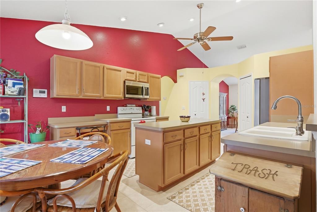 A kitchen with light wood cabinets, a center island, and a red accent wall — 13056 PAINTED BUNTING AVENUE, WEEKI WACHEE, FL