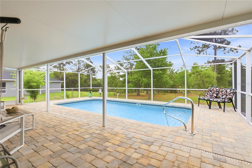 A screened-in patio features a rectangular swimming pool with pavers and a metal handrail — 13056 PAINTED BUNTING AVENUE, WEEKI WACHEE, FL