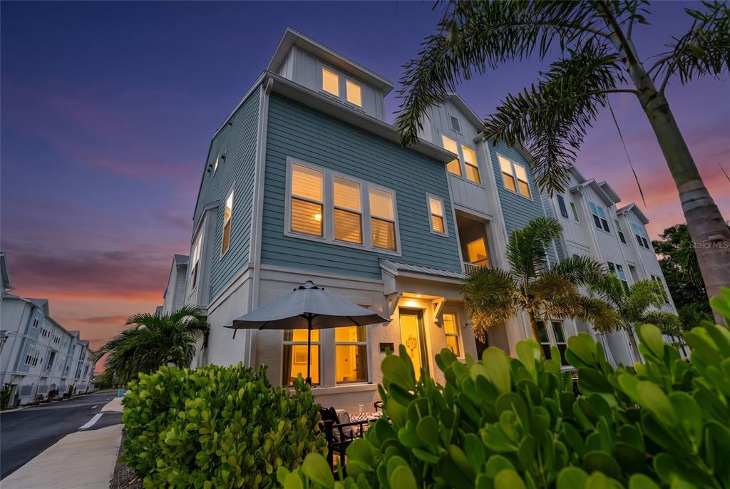 A patio with outdoor furniture and an umbrella sits outside a home's front entrance — 2501 BOONE COURT, SARASOTA, FL