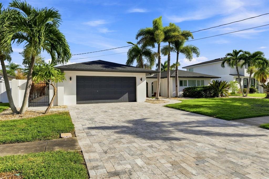 A single-story house with a dark garage door, paved driveway, and palm trees in front — 320 PALM ISLAND NE, CLEARWATER BEACH, FL