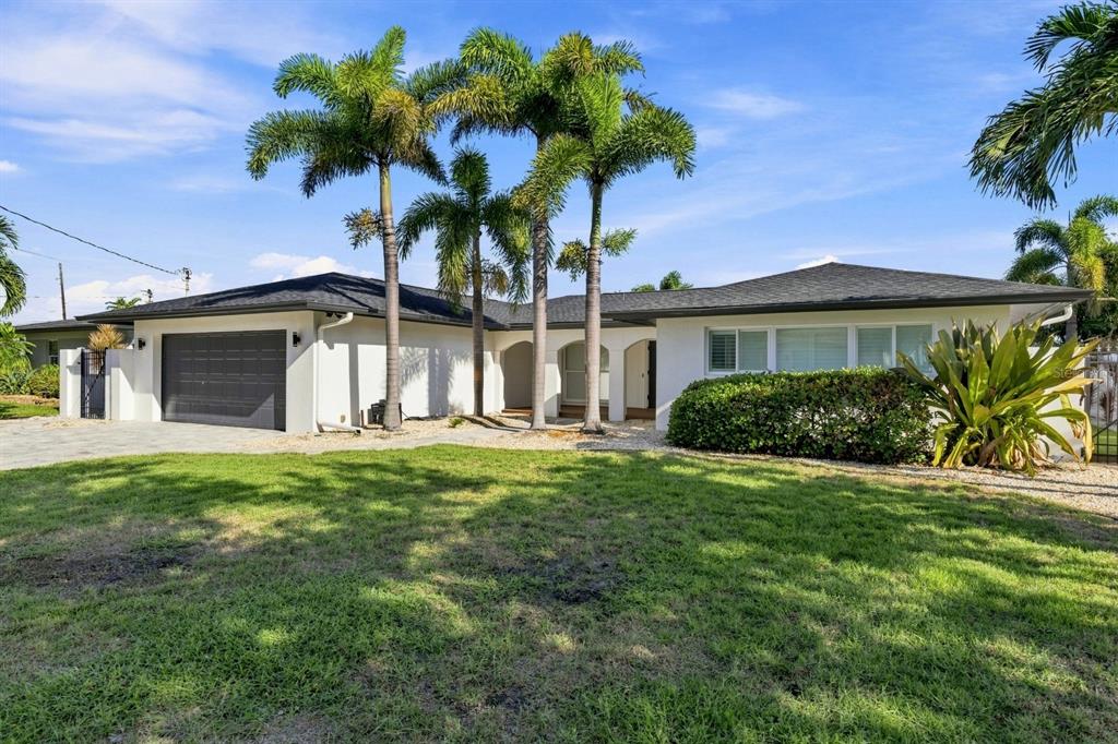 A single-story white house with a dark roof, garage, and palm trees in the yard — 320 PALM ISLAND NE, CLEARWATER BEACH, FL