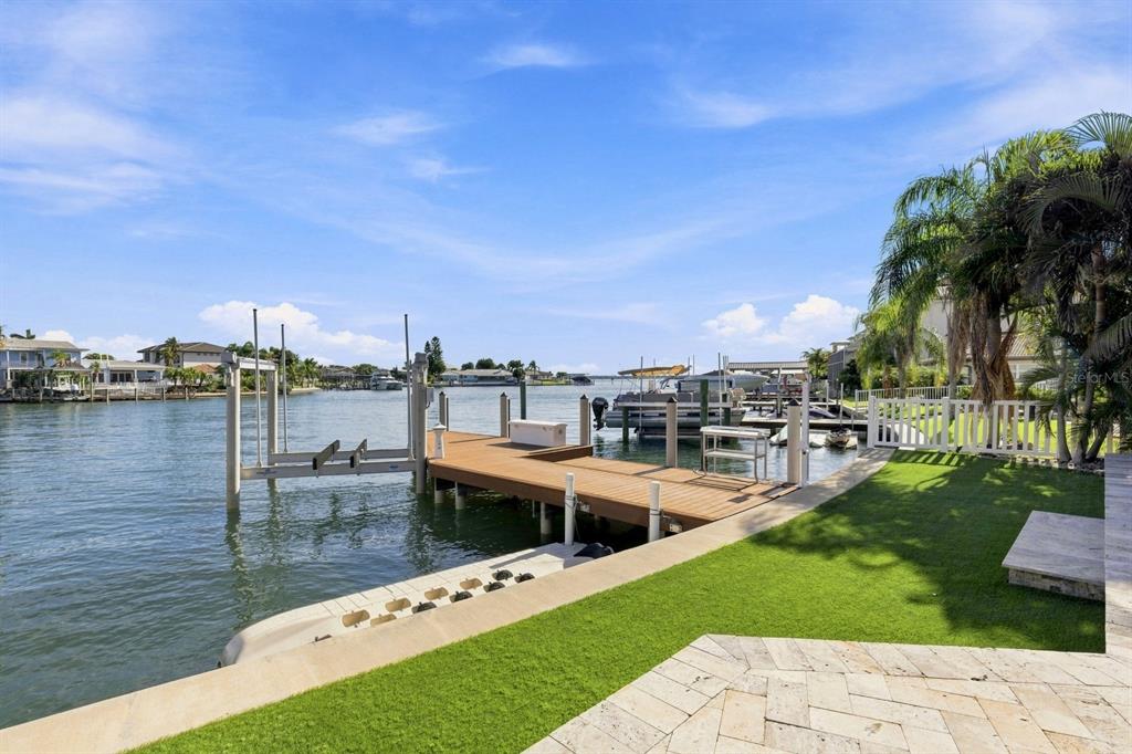 A wooden boat dock with a lift extends into a canal from a grassy backyard — 320 PALM ISLAND NE, CLEARWATER BEACH, FL