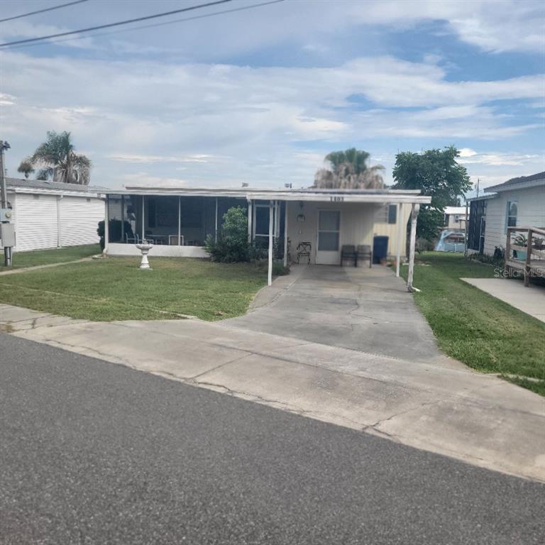 A single-story manufactured home features a screened-in porch, a concrete driveway, and a small lawn — 1403 LAKEVIEW DRIVE, TAVARES, FL