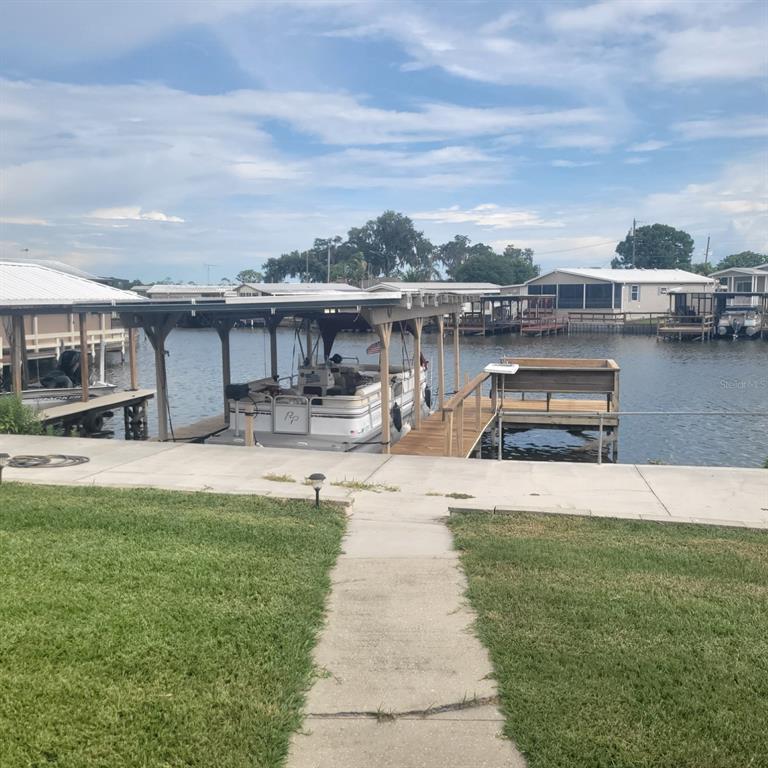 A concrete walkway leads to a covered boat dock on a canal with residential homes — 1403 LAKEVIEW DRIVE, TAVARES, FL