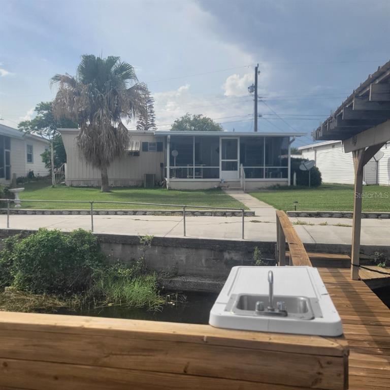 A view from a wooden dock across a canal toward a mobile home with a porch — 1403 LAKEVIEW DRIVE, TAVARES, FL