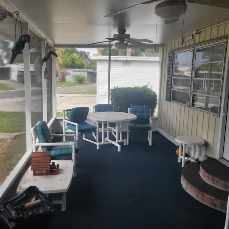 A screened-in porch features blue carpet, a white table with chairs, and a ceiling fan — 1403 LAKEVIEW DRIVE, TAVARES, FL