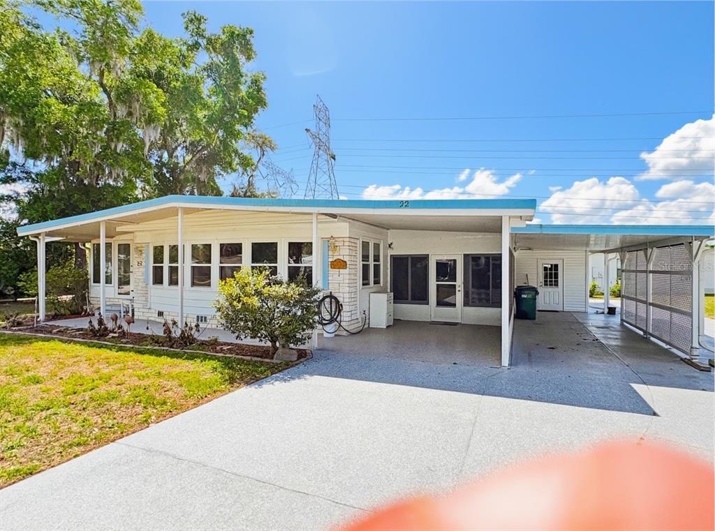 A single-story mobile home with a carport, white siding, and a concrete driveway — 22 S BOBWHITE ROAD, WILDWOOD, FL