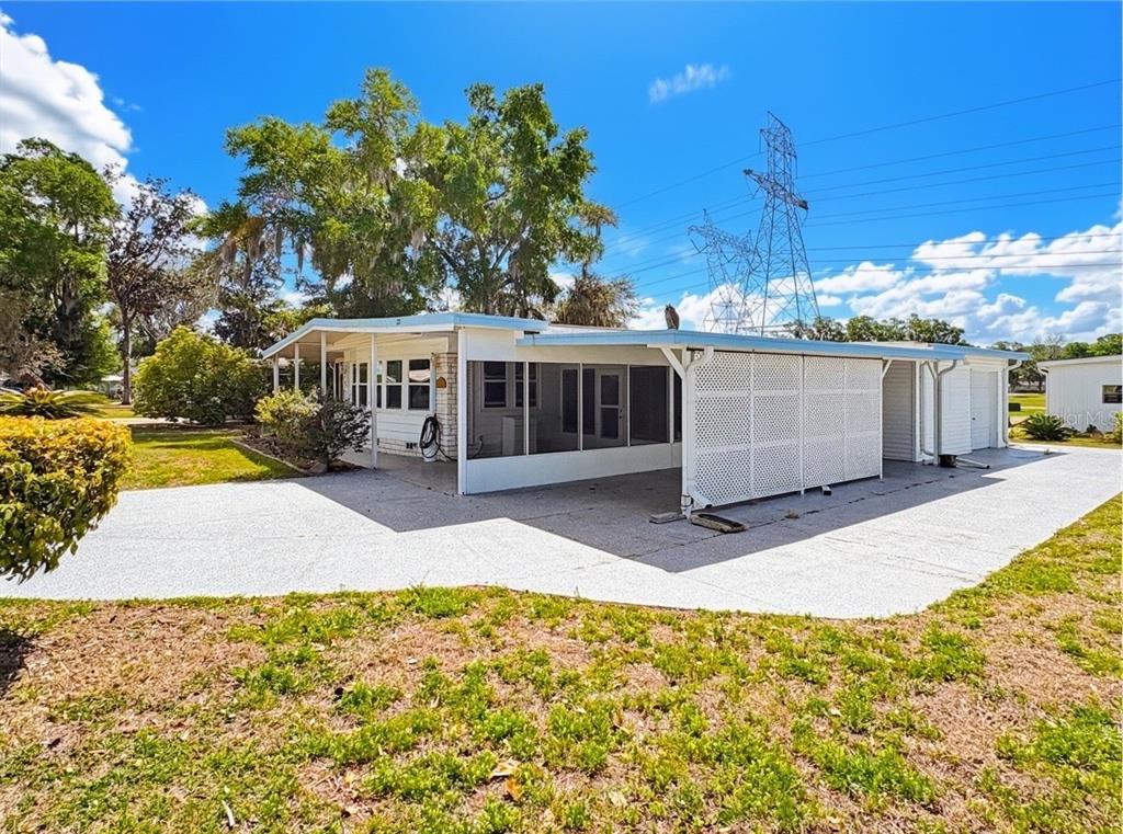 A white manufactured home features a large screened-in porch and a concrete driveway — 22 S BOBWHITE ROAD, WILDWOOD, FL