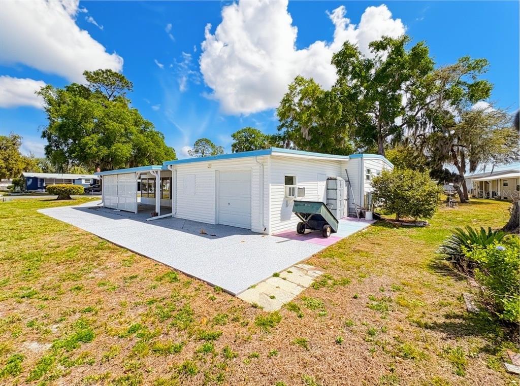 A white mobile home with a garage and a concrete patio under a blue sky — 22 S BOBWHITE ROAD, WILDWOOD, FL