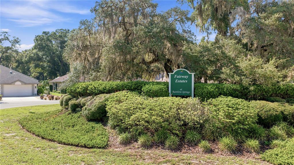 A green sign for Fairway Estates at Rainbow Springs stands behind a landscaped garden — 8939 SW 194TH COURT, DUNNELLON, FL