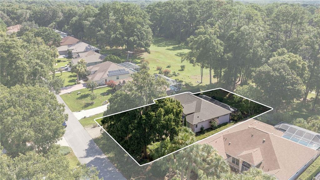 An aerial view shows a residential house with a screened pool enclosure and surrounding trees — 8939 SW 194TH COURT, DUNNELLON, FL