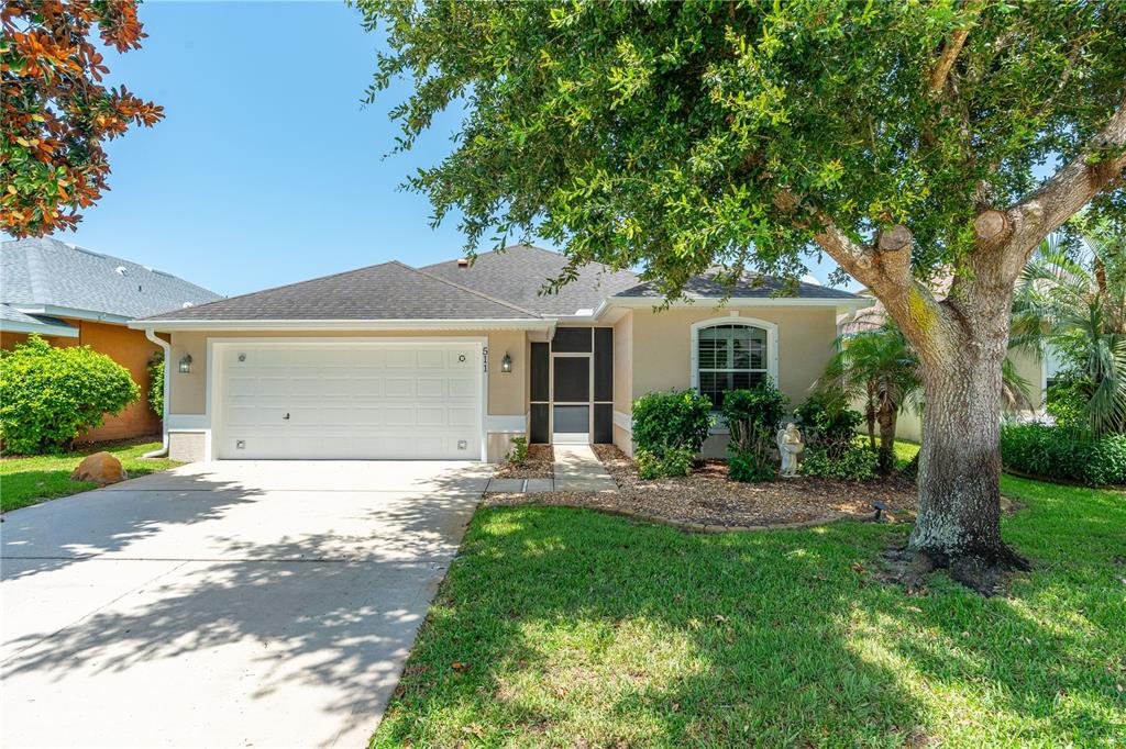 A single-story house with a two-car garage, a front walkway, and a large shade tree — 511 SAFE HARBOR DRIVE, EDGEWATER, FL