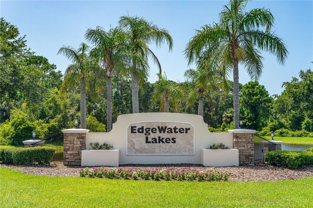 A stone and stucco monument sign for Edgewater Lakes stands before palm trees and greenery — 511 SAFE HARBOR DRIVE, EDGEWATER, FL
