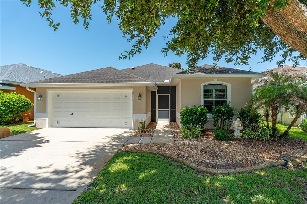 A single-story house with a two-car garage, a screened entryway, and a landscaped front yard — 511 SAFE HARBOR DRIVE, EDGEWATER, FL
