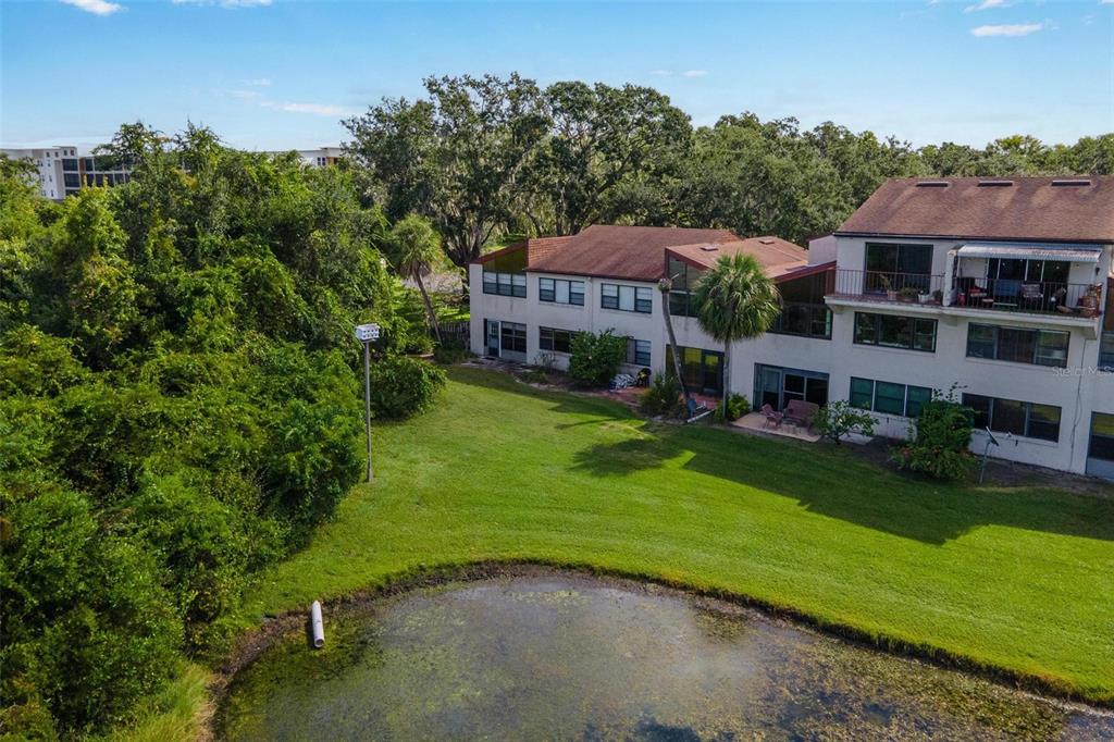 An exterior view of a multi-story apartment building overlooking a small pond and lawn — 4300 BAYWOOD BOULEVARD UNIT B106, MOUNT DORA, FL