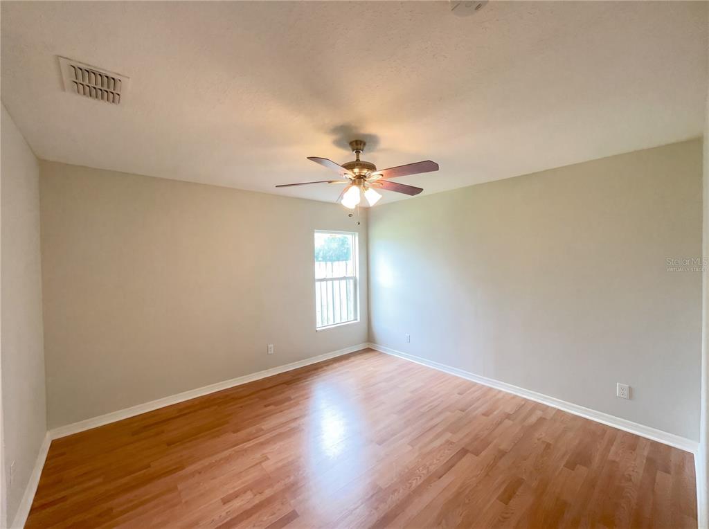 An empty room features light-colored walls, a ceiling fan, and wood-look flooring — 1801 MISSOURI AVENUE, ST CLOUD, FL