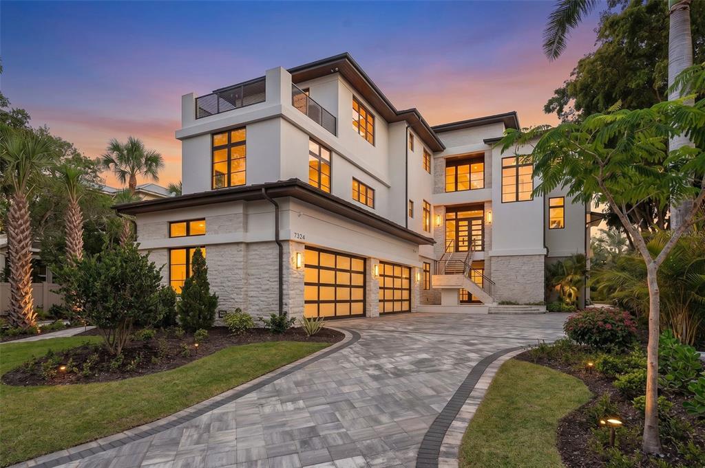 A three-story modern house with a stone facade, a two-car garage, and a paved driveway — 7324 POINT OF ROCKS ROAD, SARASOTA, FL