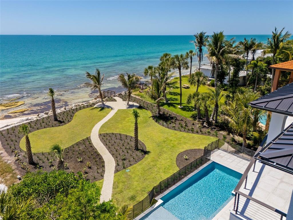 An aerial view of a coastal property featuring a swimming pool, lawn, and oceanfront beach — 7324 POINT OF ROCKS ROAD, SARASOTA, FL