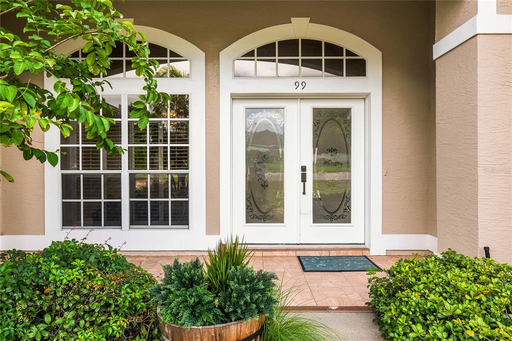A front entrance features double glass-paneled doors with a transom window and a house number — 99 HOLLOW PINE DRIVE, DEBARY, FL