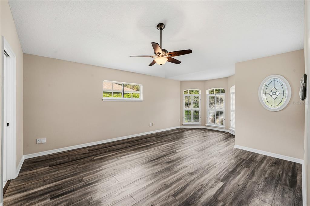 An empty room with wood-look flooring, a ceiling fan, and several windows — 99 HOLLOW PINE DRIVE, DEBARY, FL