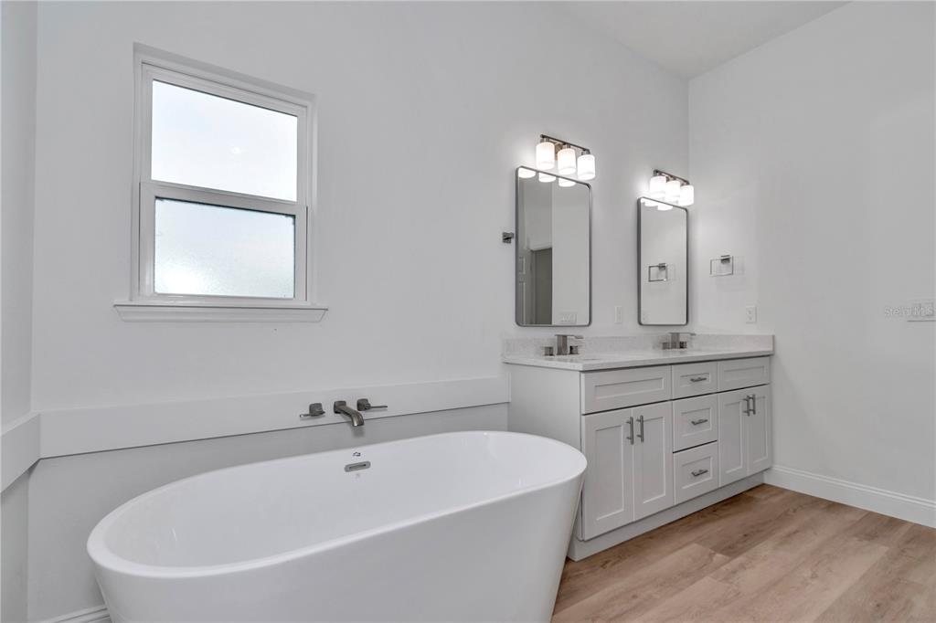 A modern bathroom features a white freestanding tub, a double vanity, and two wall mirrors — 13530 SW 47TH CIRCLE, OCALA, FL