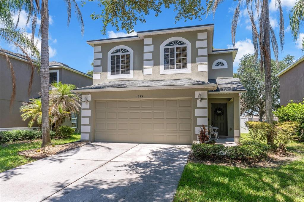 A two-story house with a beige stucco exterior, a two-car garage, and arched upper windows — 1944 PORTCASTLE CIRCLE, WINTER GARDEN, FL