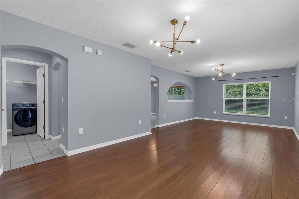 An open living area features light blue walls, wood-look flooring, and two modern light fixtures — 1944 PORTCASTLE CIRCLE, WINTER GARDEN, FL