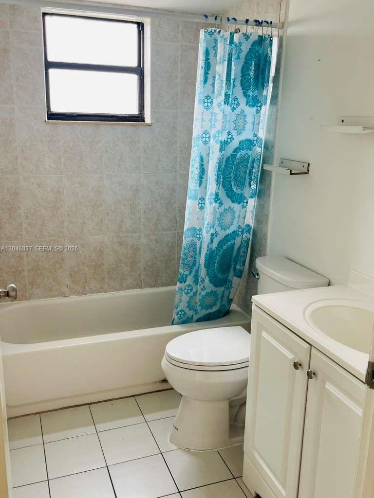 A bathroom features a white vanity, a toilet, and a bathtub with a blue curtain — 8075 NW 7th St # 520, Miami FL 33126, MIAMI, FL