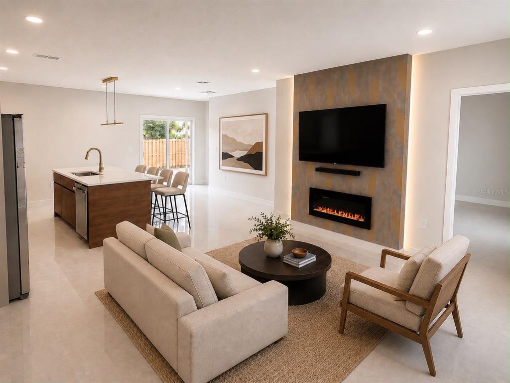 An open-concept living room features a modern fireplace, wall-mounted television, and an adjacent kitchen island — 1365 SANDUSKY STREET SE, PALM BAY, FL