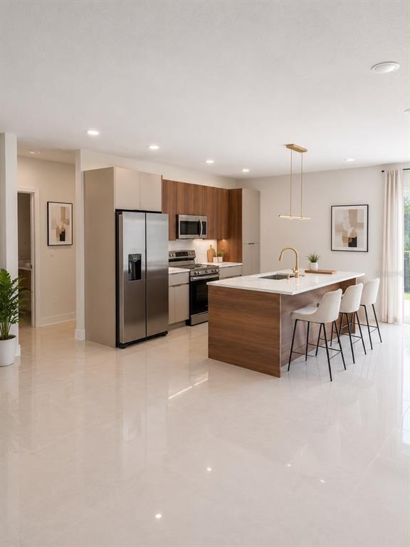 A modern kitchen features wood-toned cabinetry, stainless steel appliances, and a central island with seating — 1365 SANDUSKY STREET SE, PALM BAY, FL