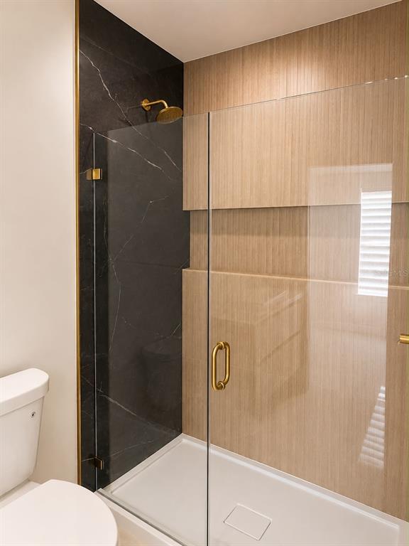 A bathroom features a glass-enclosed shower with black marble and light wood-look tile walls — 1365 SANDUSKY STREET SE, PALM BAY, FL