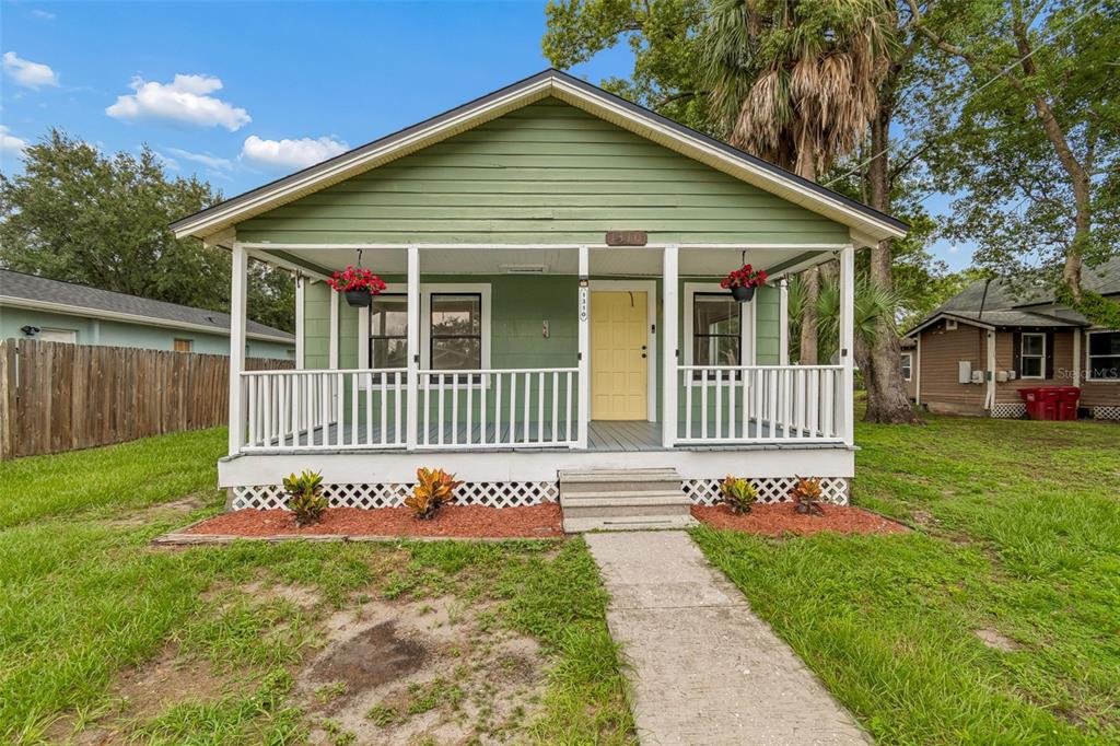 A green house with a front porch, white railings, and a yellow door — 1310 N FRANKLIN STREET, PLANT CITY, FL