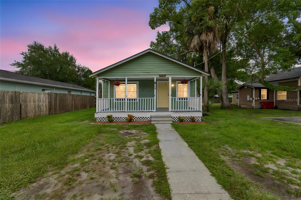 A green house with a front porch and a walkway sits on a grassy lot — 1310 N FRANKLIN STREET, PLANT CITY, FL