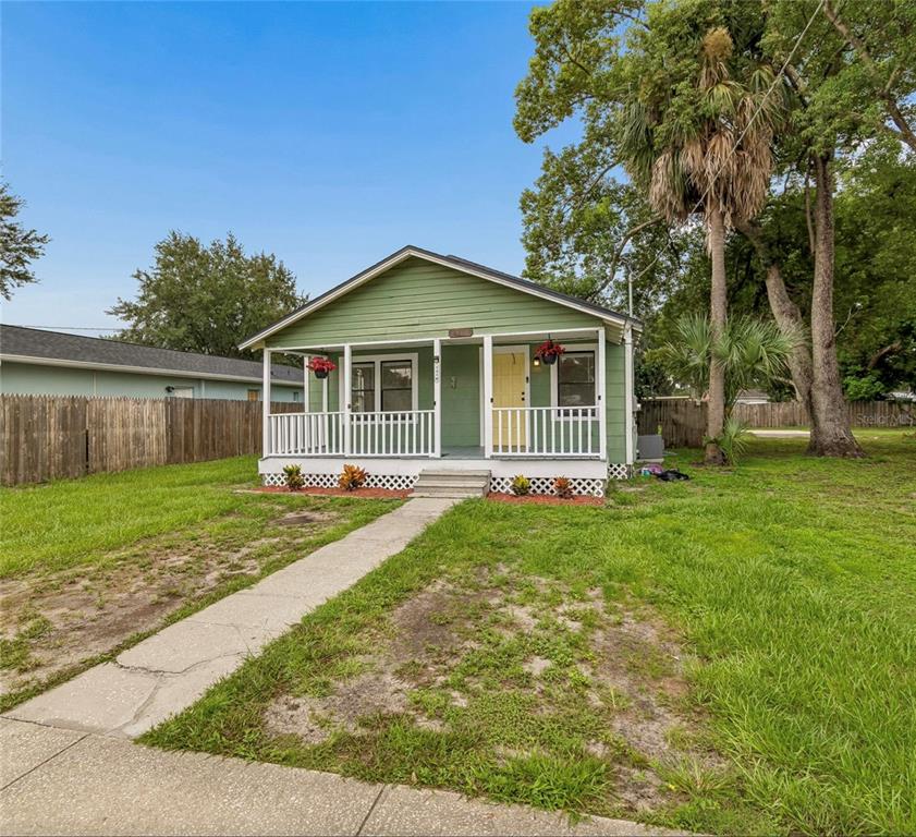 A green, single-story house with a front porch, yellow door, and a concrete walkway — 1310 N FRANKLIN STREET, PLANT CITY, FL