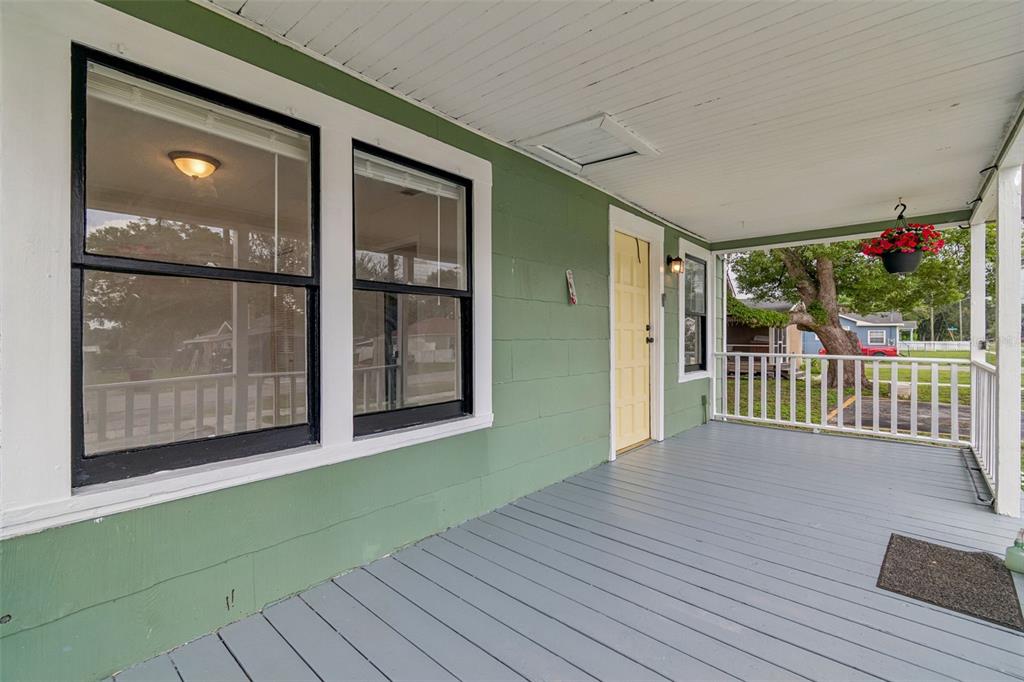 A covered front porch with green siding, a yellow door, and gray painted wooden flooring — 1310 N FRANKLIN STREET, PLANT CITY, FL