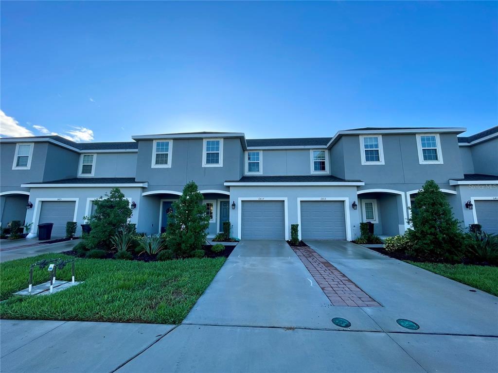 A row of two-story townhomes features gray siding, attached garages, and small front lawns — 6417 FAIRMONT LANE, PALMETTO, FL