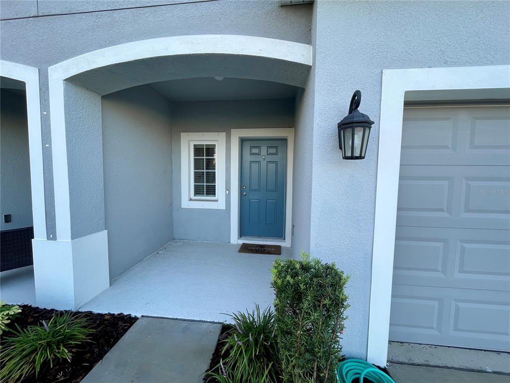 The exterior of a home features a blue front door, a window, and a garage — 6417 FAIRMONT LANE, PALMETTO, FL